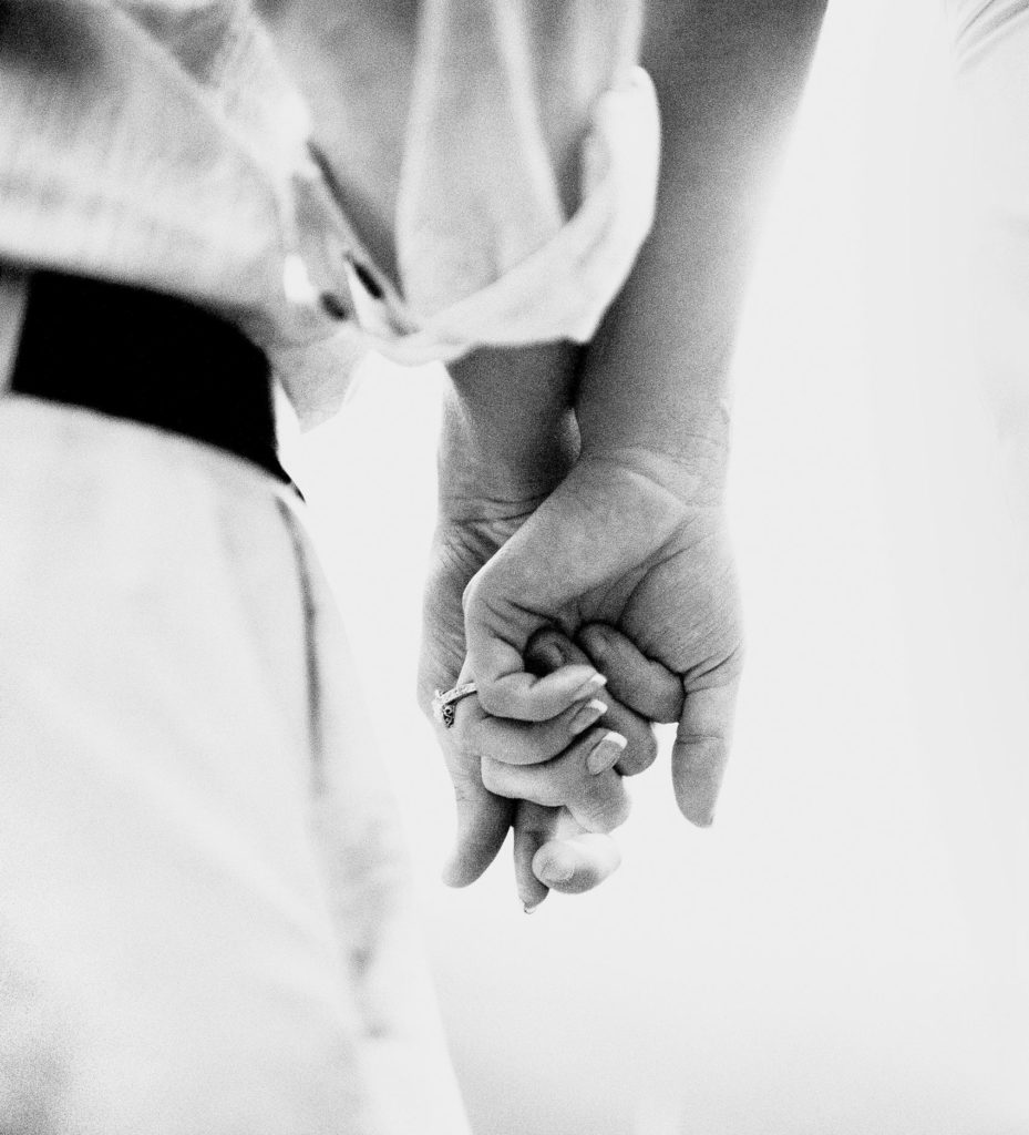 Couple holding hands showing engagement ring