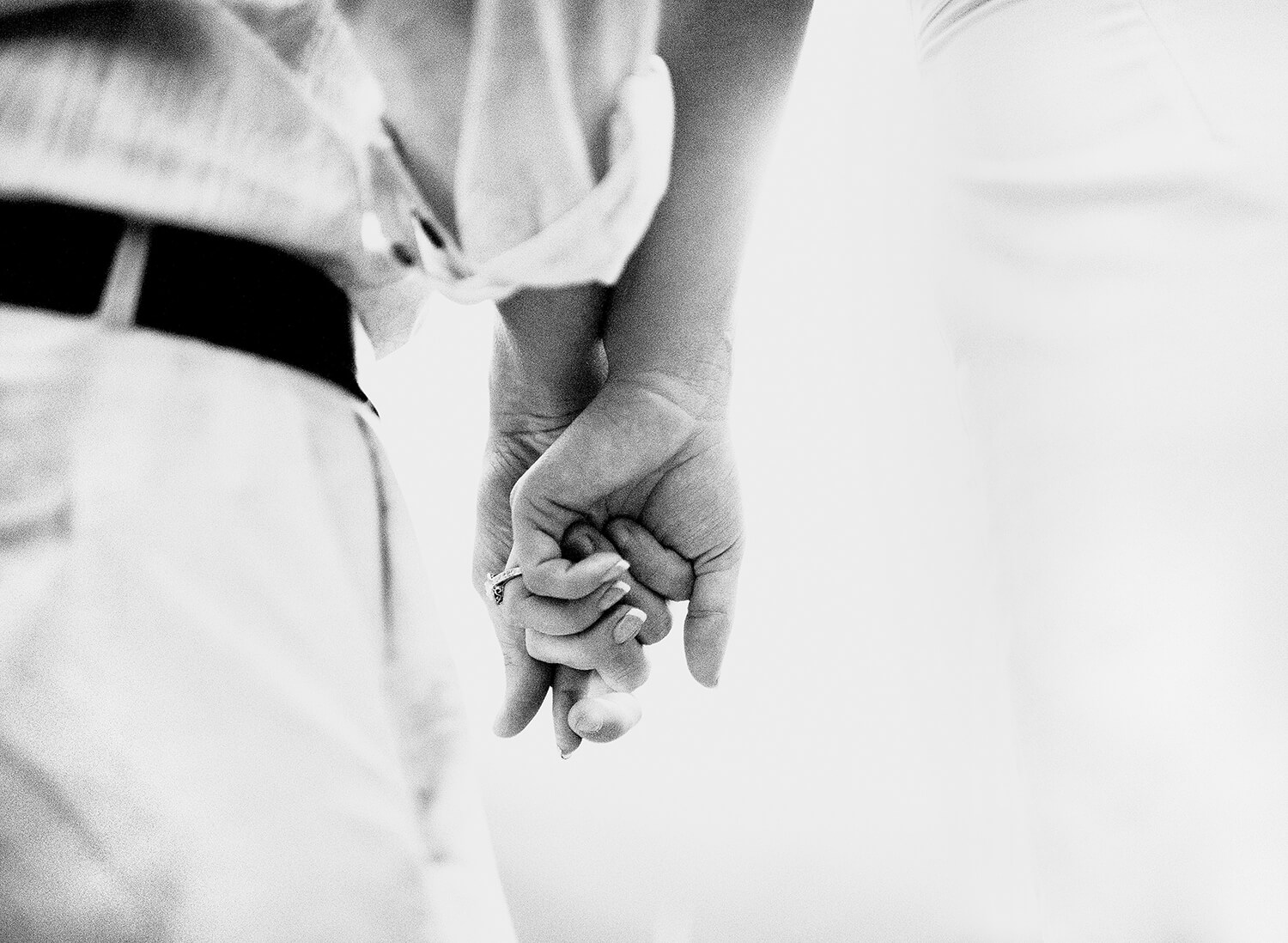 Couple holding hands showing diamond engagement ring