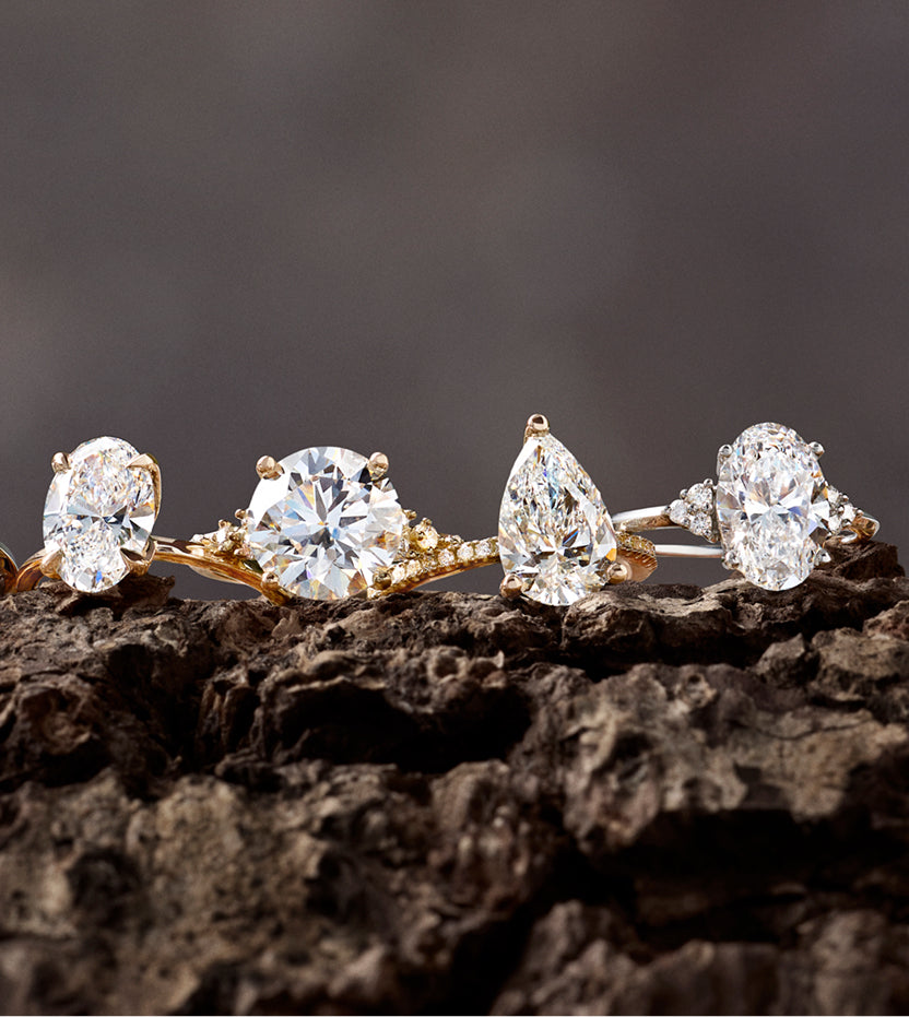 Oval, round, pear and oval three-stone diamond engagement rings in a row
